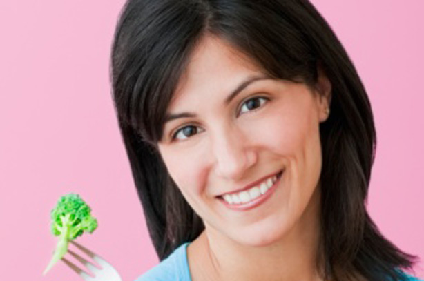 A woman eating some broccoli