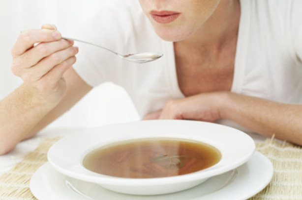 A woman eating a bowl off cabbage soup