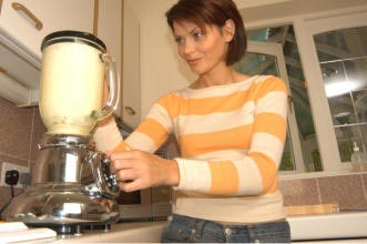 A woman in her kitchen belnding smoothies