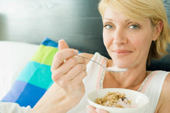 A woman eating a breakfast of cereal and yogurt