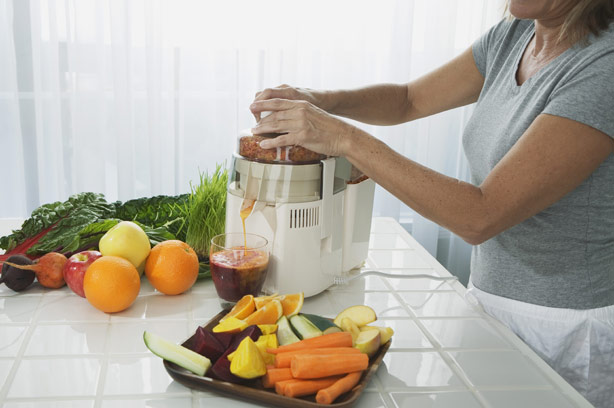 A woman in the kitchen preparing vegetable and fruit juice smoothie A woman in the kitchen preparing vegetable and fruit juice smoothie