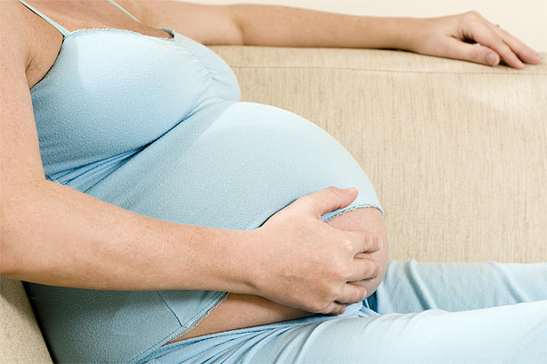 Pregnant woman with a hand on her bump Pregnant woman with a hand on her bump