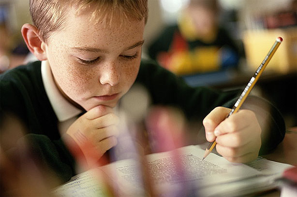 Boy in classroom with pencil and workbook