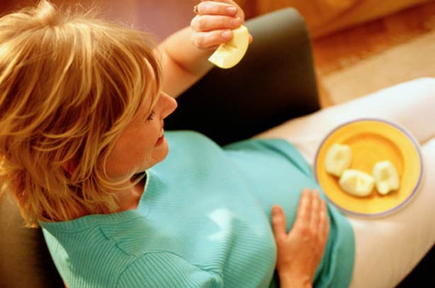 A pregnant women eating apples