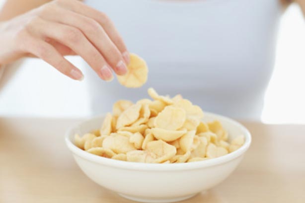 A woman eating a bowl of crisps