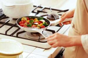 A woman frying vegetables in her kitchen A woman frying vegetables in her kitchen