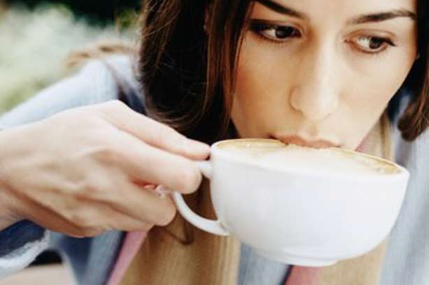 A womaning drking a cup of coffee