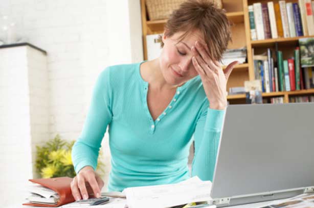 A woman looking stressed sitting at her laptop computer