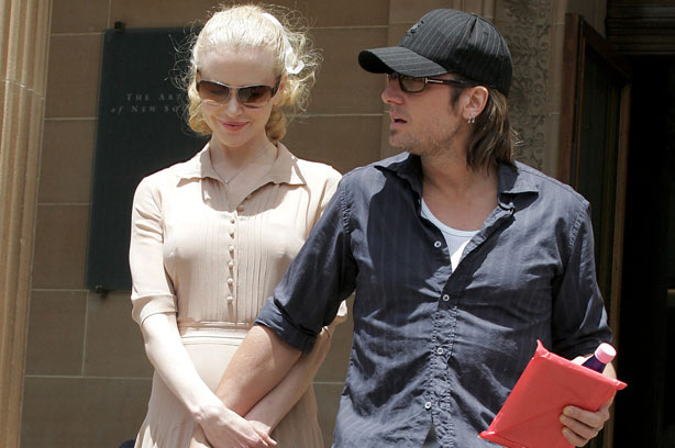 Pregnant Nicole Kidman and husband Keith Urban walk down steps with his hand covering her baby bump