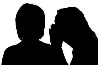 Silhouette of a woman whispering into another woman's ear