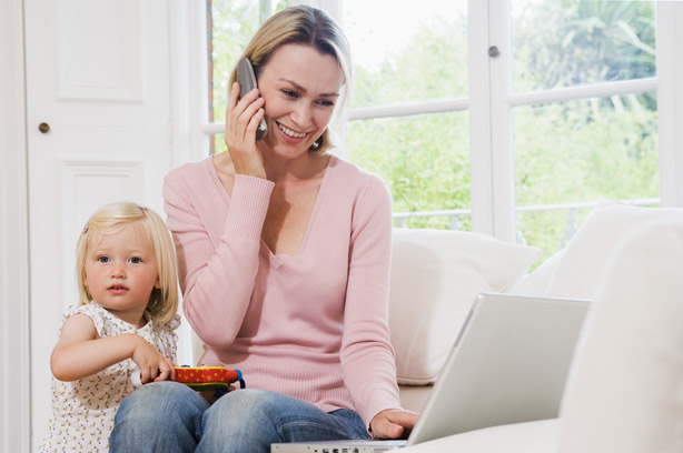 Woman on a laptop talking on the phone with her child