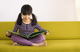 A young girl reading a book on a sofa A young girl reading a book on a sofa