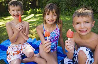 Three children enjoying ice lollies in the shade