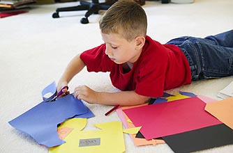 A boy using paper and scissors to make a scrapbook