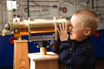 Boy in a museum looking through a telescope