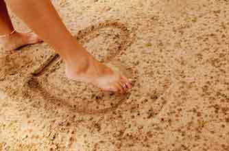 Woman making heart shape with her foot in the sand_rex