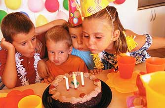 Kids blowing out candles on a birthday cake