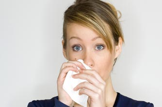 A woman using a tissue A woman using a tissue