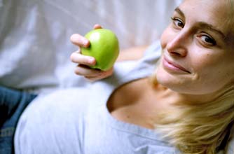 Pregnant woman eating an apple using the health in pregnancy grant