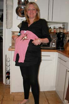 Anna at 39 weeks pregnant holding a babygro up against her bump