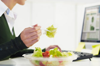 woman eating lunch at her desk woman eating lunch at her desk