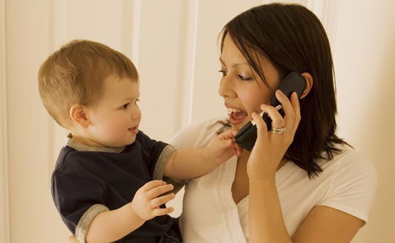 Mum talking on the phone while holding her son Mum talking on the phone while holding her son