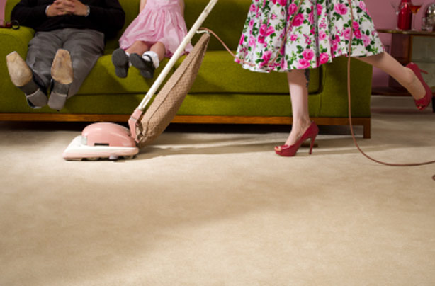 Woman hoovering under husband's feet Woman hoovering under husband's feet