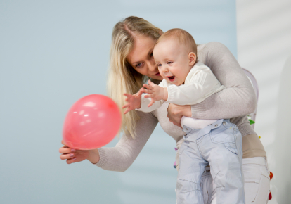 Mother and baby playing with a red balloon Mother and baby playing with a red balloon