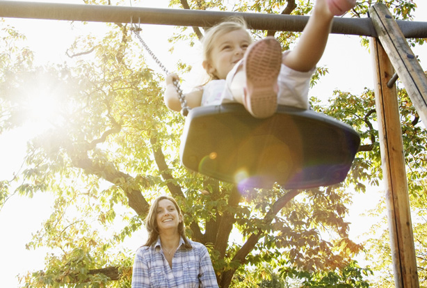 woman pushing child on swing woman pushing child on swing