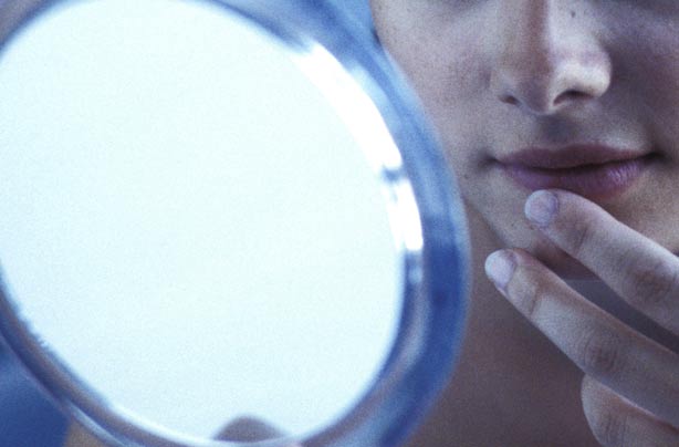 Teenager looking at spots in the mirror