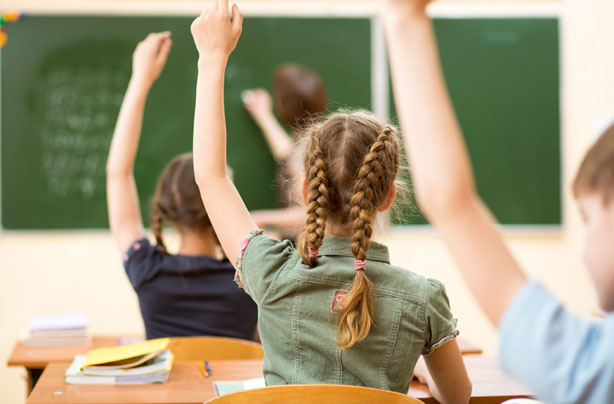 Children with hands up in classroom