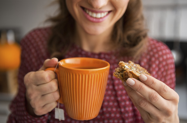 Woman drinking tea, eating cake, snacking