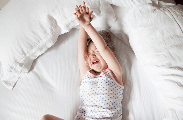 Toddler having a tantrum, girl in bed crying